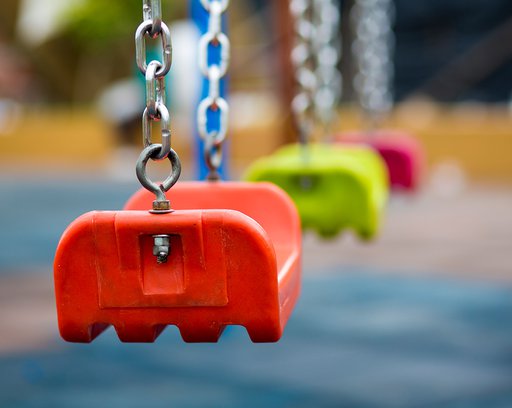 Close up of orange plastic colored swing in playground